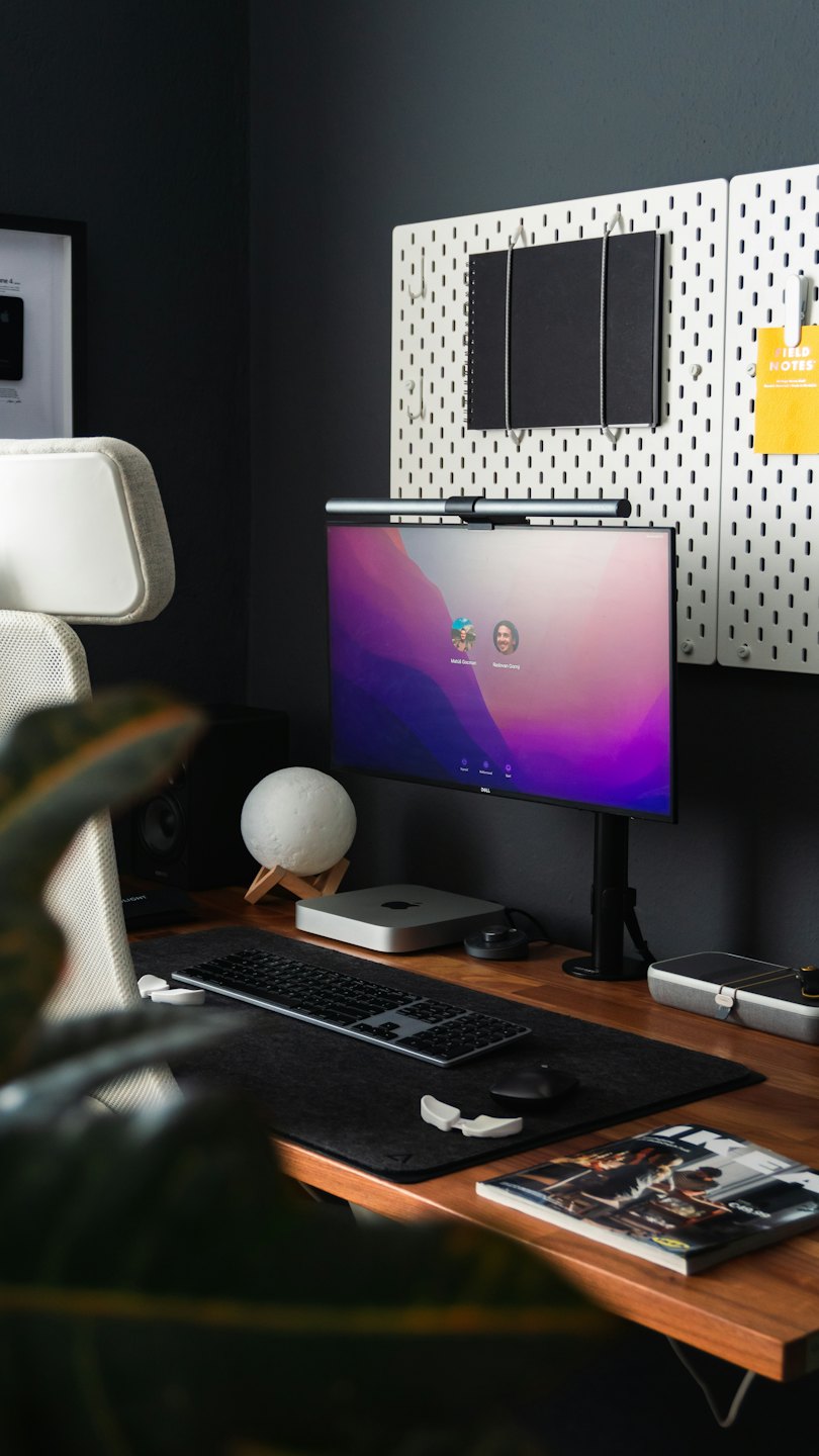 Minimalist home office with desktop monitor and keyboard on a wood desk.